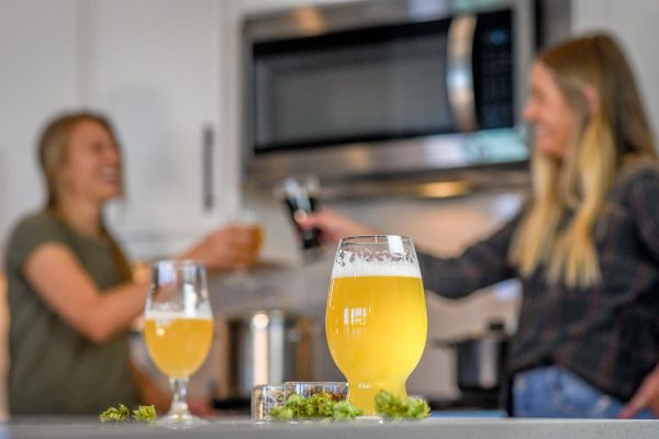 Glasses of beer with homebrewers cheersing in background