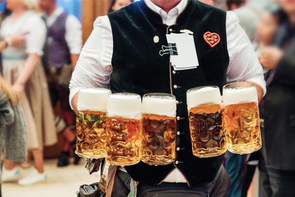 Person carrying large mugs of German beer