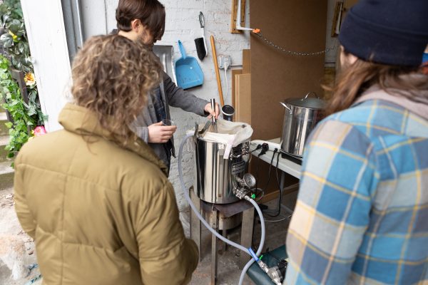 Three homebrewers standing around a brewing system.